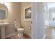 A well-lit powder room with a pedestal sink, toilet, and decorative artwork, showcasing a clean and functional design at 4035 Bucolic Loop, Myrtle Beach, SC 29588