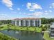 Exterior view of a multi-story condo building with balconies overlooking a well-manicured lawn and pond with fountain at 4440 Nassau Ct. # 502, Little River, SC 29566