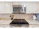 Close up on a kitchen cooktop with stainless steel microwave and decorative backsplash at 4440 Nassau Ct. # 502, Little River, SC 29566