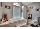 Relaxing bathroom featuring a jetted tub, neutral walls, and a large window for natural light at 451 Holly View Ln., Loris, SC 29569