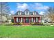 Charming red brick home featuring a rocking chair front porch, well-manicured lawn, and inviting curb appeal at 451 Holly View Ln., Loris, SC 29569