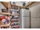 Well-stocked pantry featuring custom wooden shelving, a microwave, and a full-sized refrigerator at 451 Holly View Ln., Loris, SC 29569