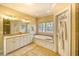 Elegant bathroom with a soaking tub, double vanity, and natural light from a large window at 4514 Wagon Run Circle, Murrells Inlet, SC 29576