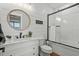Bright bathroom featuring a white vanity, round mirror, and tub-shower with glass doors at 5100 Ocean Blvd. N, North Myrtle Beach, SC 29582