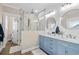Bathroom featuring double vanity with blue cabinets and a glass shower with marble tile at 5100 Ocean Blvd. N, North Myrtle Beach, SC 29582