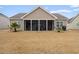 A backyard view of the home with a screened porch and manicured lawn featuring young palm trees on each side at 545 Tourmaline Dr., Little River, SC 29566