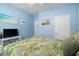 This bright bedroom features a ceiling fan, blue walls, and a tropical-themed bedspread at 545 Tourmaline Dr., Little River, SC 29566