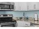 Galley kitchen featuring stainless appliances, granite countertops, and white cabinets at 5523 N Ocean Blvd. # 1101, Myrtle Beach, SC 29577