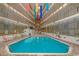Large indoor swimming pool with lounge chairs and tables, under a brightly decorated ceiling at 5905 S Kings Hwy. # 216B, Myrtle Beach, SC 29577