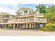 Inviting two-story beach house with a wide porch, an upper deck, black shutters, and a spacious ground-level parking area at 6001 - Mh69B South Kings Hwy., Myrtle Beach, SC 29575