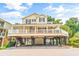 Charming yellow two-story beach home featuring a spacious porch, black shutters, and parking and storage space beneath the raised structure at 6001 - Mh69B South Kings Hwy., Myrtle Beach, SC 29575