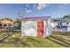 Well-maintained white shed with a red metal roof and a red door, surrounded by grass and a fence at 602 Luttie Rd., Myrtle Beach, SC 29588