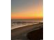 Tranquil beach scene at twilight features the ocean and a silhouette of a wooden pier under a golden sky at 6200 N Ocean Blvd. # 501, North Myrtle Beach, SC 29582