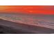A scenic beach view features a fiery red sky, waves rolling into shore, and people walking along the sand at 6200 N Ocean Blvd. # 501, North Myrtle Beach, SC 29582