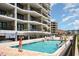 Outdoor pool area with vacationers and views of the condo buildings at 6200 N Ocean Blvd. # 501, North Myrtle Beach, SC 29582