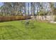 Green backyard with a metal table and chairs surrounded by mature trees and fencing at 11 Ryan Ln., Myrtle Beach, SC 29579