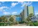 Wide shot of the Coral Beach Resort, showcasing its unique architecture and beautiful landscaping with many palm trees at 1105 S Ocean Blvd. # 446, Myrtle Beach, SC 29577