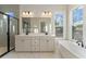 Bathroom featuring double sinks, a glass-enclosed shower, a freestanding tub, and large windows at 115 S Middleton Dr. Nw, Calabash, NC 28467