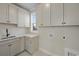 A bright laundry room features white cabinets, a sink, counter space, and washer/dryer hookups at 115 S Middleton Dr. Nw, Calabash, NC 28467