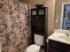 Cozy bathroom features a floral shower curtain and over-the-toilet cabinet for extra storage space at 1261 Pineridge St., Conway, SC 29527