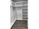 Spacious walk-in closet with custom white shelving and hanging rods and wood-look flooring at 135 Low Country Loop, Murrells Inlet, SC 29576