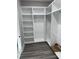 Organized walk-in closet with custom white shelving and hanging rods and wood-look flooring at 135 Low Country Loop, Murrells Inlet, SC 29576