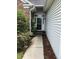 Inviting front entrance with a white door and screen, surrounded by lush greenery, leading to the home at 1372 Oakmont Ct., Murrells Inlet, SC 29576
