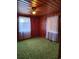 Cozy bedroom featuring wood-paneled walls, green carpet, and natural light from two windows at 1375 Kenny Jordan Rd, Tabor City, NC 28463
