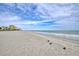Expansive sandy beach with gentle waves meeting the shore, under a bright sky with scattered clouds and distant buildings at 1501 S Ocean Blvd. # 844, Myrtle Beach, SC 29577