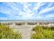 Scenic beach view with sand fences and ocean horizon beneath a partly cloudy sky, inviting relaxation and coastal charm at 1501 S Ocean Blvd. # 844, Myrtle Beach, SC 29577