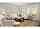 Cozy living room showcasing neutral sofas, armchairs, wood floors, a jute rug, and natural light from expansive windows at 1509 Seachase Way, North Myrtle Beach, SC 29582