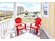 Relaxing balcony with two red Adirondack chairs offering city views and neighborhood charm at 1614-B S Ocean Blvd., Surfside Beach, SC 29575