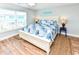 Bedroom with a large bed, wood floors, two bedside lamps, and a large window at 1614-B S Ocean Blvd., Surfside Beach, SC 29575