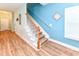 View of a carpeted staircase with wood railings and a light-filled landing with wood flooring and light blue walls at 1614-B S Ocean Blvd., Surfside Beach, SC 29575