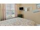 Comfortable bedroom featuring a bed with patterned comforter and matching pillows, window with blinds and mounted TV at 195 Cupola Dr., Longs, SC 29568