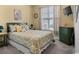 A cozy bedroom featuring a queen-sized bed with a patterned comforter and matching shams, a mounted TV, and large window at 195 Cupola Dr., Longs, SC 29568