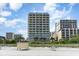 Multi-story condo complex surrounded by sand, vegetation, and palm trees on a clear day at 200 76Th Ave. N # 410, Myrtle Beach, SC 29572
