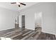 Main bedroom with tray ceiling, wood-look flooring, ceiling fan, and two doorways to en-suite bath and closet at 272 Stillbrook Dr., Longs, SC 29568