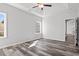 Bright main bedroom with wood-look floors, tray ceiling, two windows, and access to walk-in closet and bathroom at 272 Stillbrook Dr., Longs, SC 29568