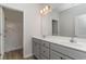 Bright bathroom featuring double sinks, grey cabinets, and a view of a walk-in shower through the doorway at 276 Stillbrook Dr., Longs, SC 29568