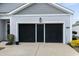 A two car garage with black screens and a well-maintained lawn and plants at 2882 Ophelia Way, Myrtle Beach, SC 29577