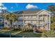 Spacious yellow condominium featuring multiple levels, white railings, a well manicured lawn, and mature palm trees at 4173 Hibiscus Dr. # 204, Little River, SC 29566