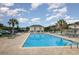 Outdoor swimming pool with chairs, palm trees, a safety fence, and a cabana at 4445 Kingsport Rd. # 406, Little River, SC 29566