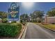 Community entrance sign and paved road with lush greenery leading into Lightkeepers Village at 4545 Lighthouse Dr. # 28C, Little River, SC 29566