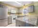 The updated kitchen boasts gray cabinets, granite countertops, and stainless steel refrigerator at 6006 Quinn Rd., Myrtle Beach, SC 29579
