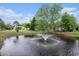 Community pond featuring a fountain, surrounded by lush greenery and mature trees under a blue sky at 6006 Quinn Rd., Myrtle Beach, SC 29579