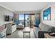 Cozy living room with a gray sofa, TV, ocean-view balcony, and coastal-themed decor at 7200 N Ocean Blvd. # 662, Myrtle Beach, SC 29572