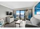 Living room featuring a gray sofa, TV, and sliding glass doors with a view of the ocean and balcony at 7200 N Ocean Blvd. # 662, Myrtle Beach, SC 29572