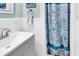 Clean bathroom with a blue floral shower curtain and white tiled walls at 7714 Woodland Dr., Myrtle Beach, SC 29572