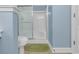A blue bathroom featuring a toilet, shower with glass door and green rug at 881 Palmetto Trail # 103, Myrtle Beach, SC 29577